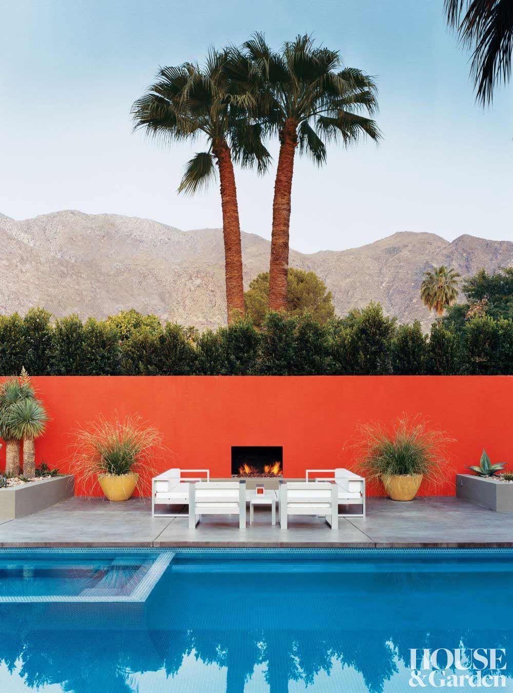 White outdoor setting by pool with red fence.